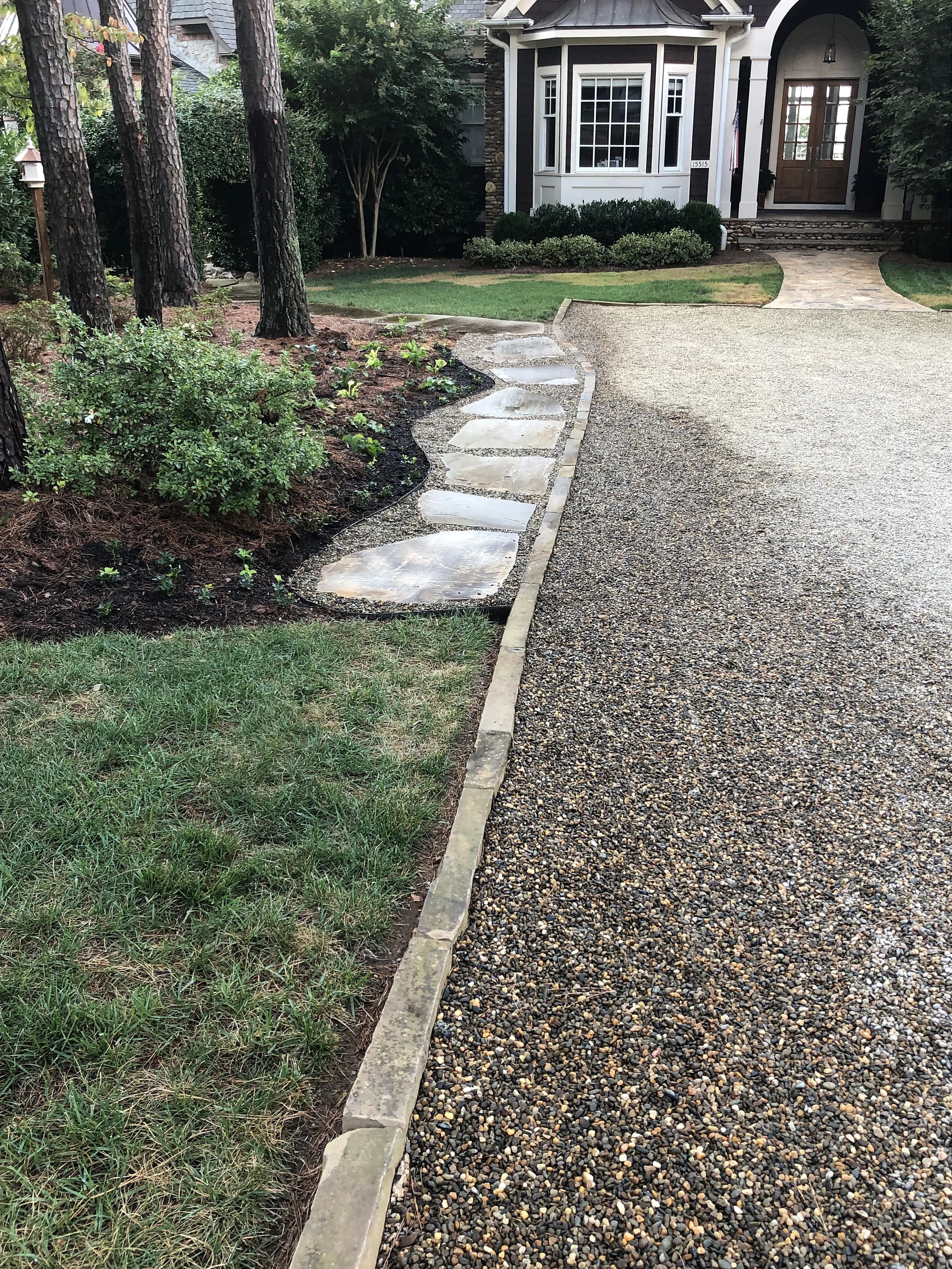 A flagstone stepping-stone path running beside a pea-gravel driveway