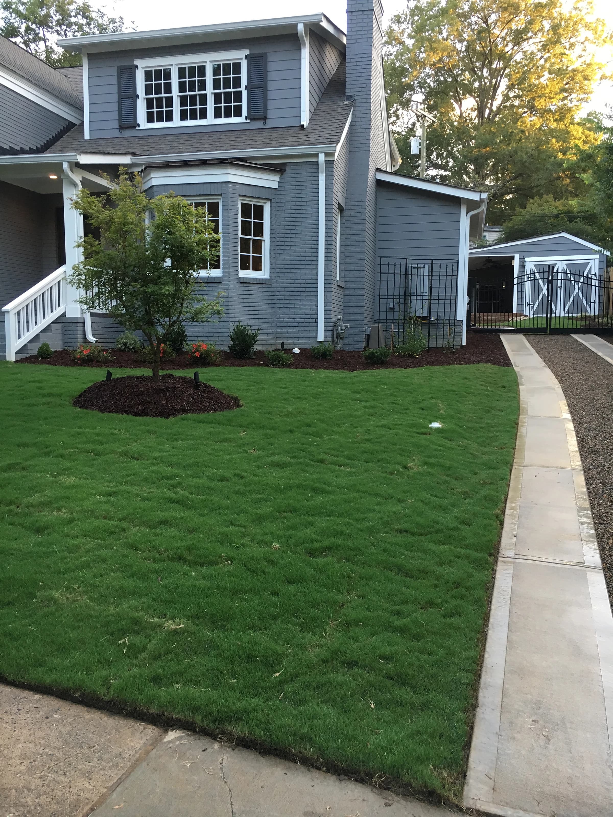 A finished front lawn and mulch bed in front of a grey-clad house