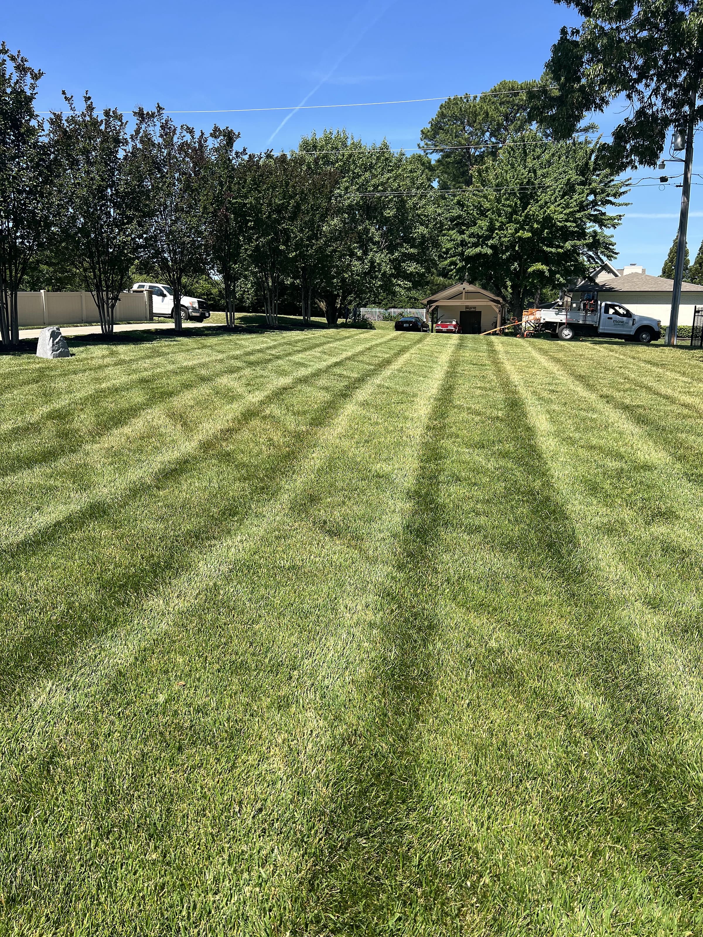 A large open lawn mowed in crisp narrow stripes running toward a tree line