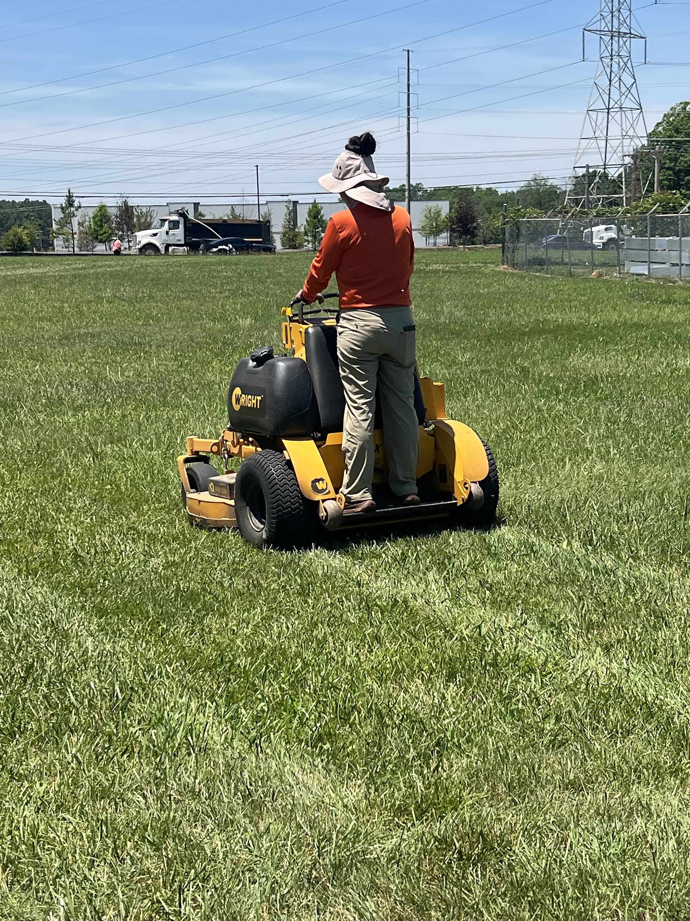 A crew member mowing a wide commercial lawn on a stand-on mower