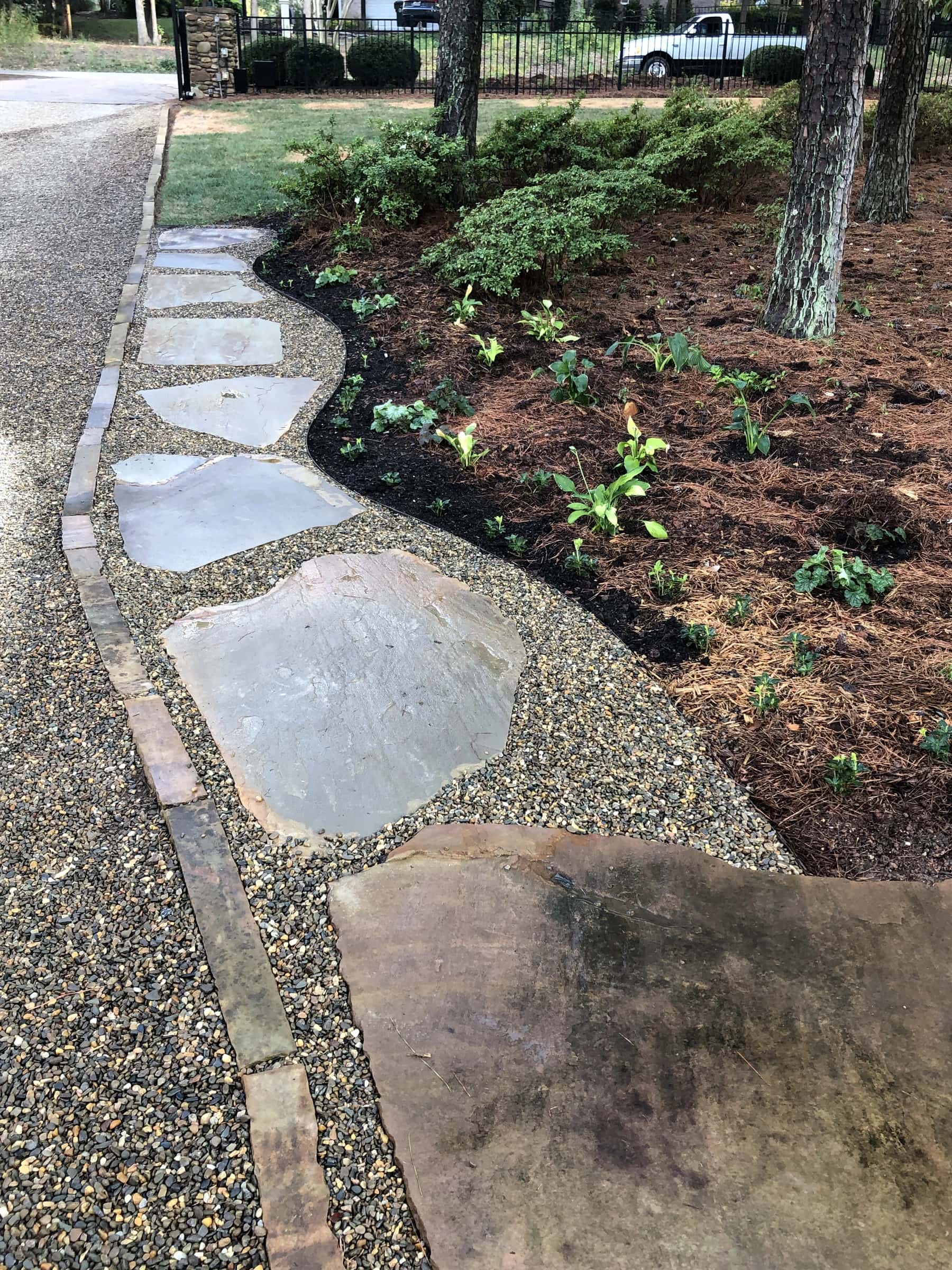 Flagstone stepping stones set through pea gravel beside a freshly mulched bed