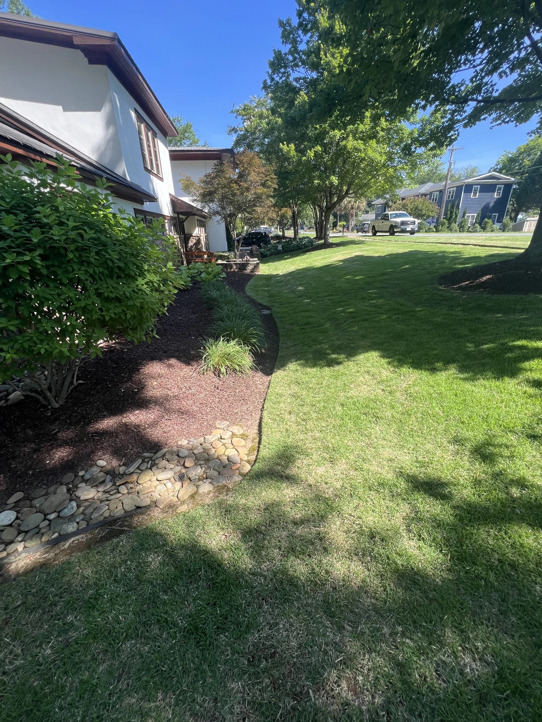 A side lawn and mulched foundation bed running along the side of a home