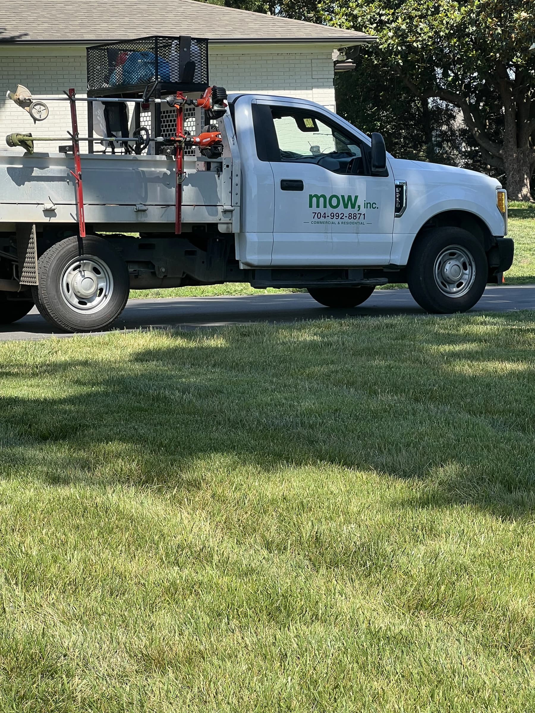 A branded Mow, Inc. service truck parked at a residential job site