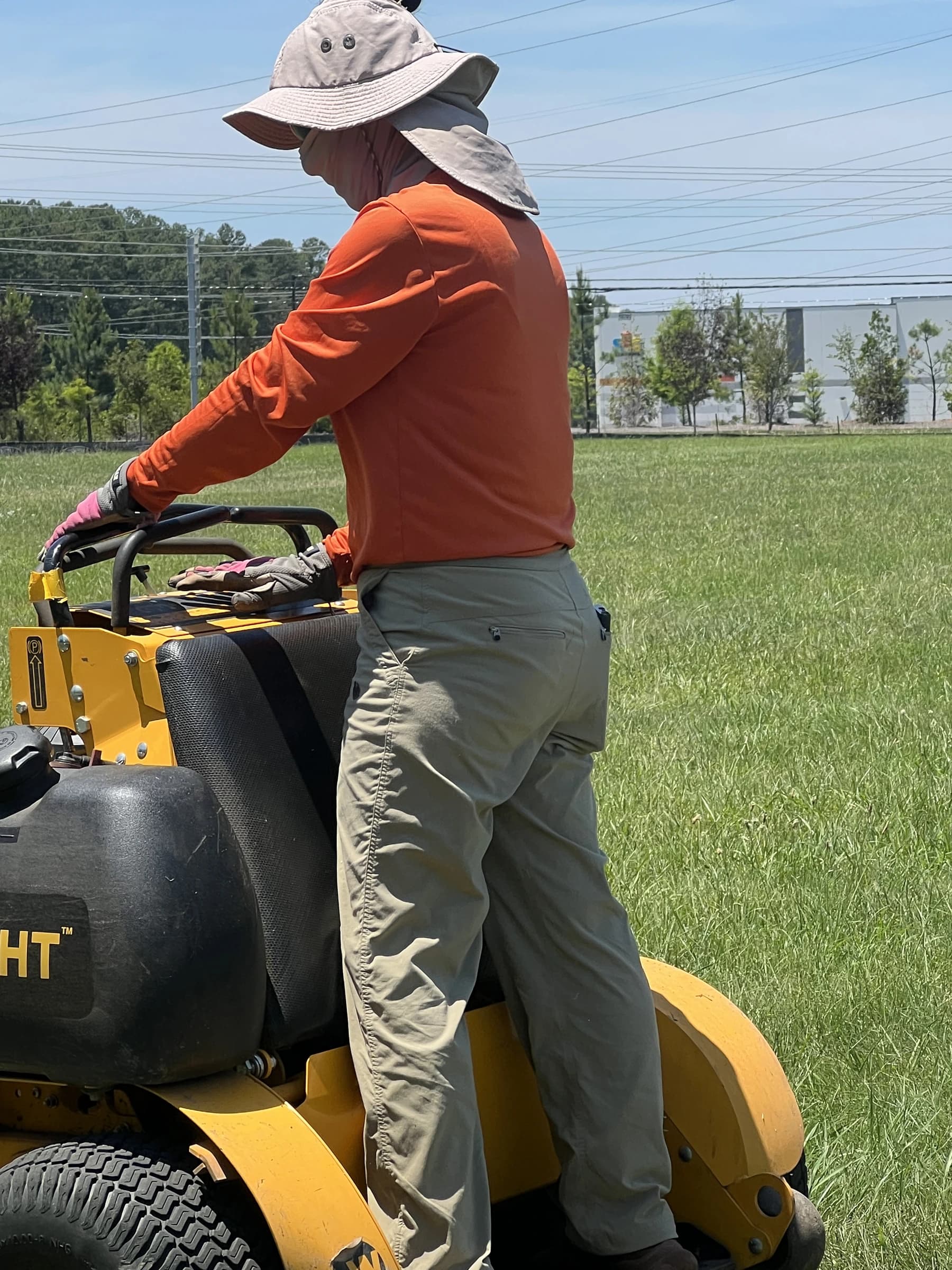 A Mow, Inc. crew member at the controls of a stand-on mower on a large property